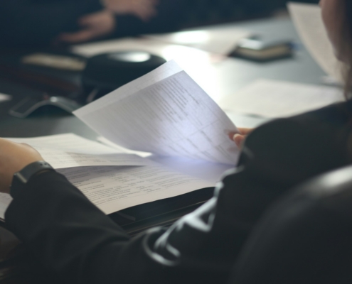 Professional reviewing accreditation standards documents at a conference table