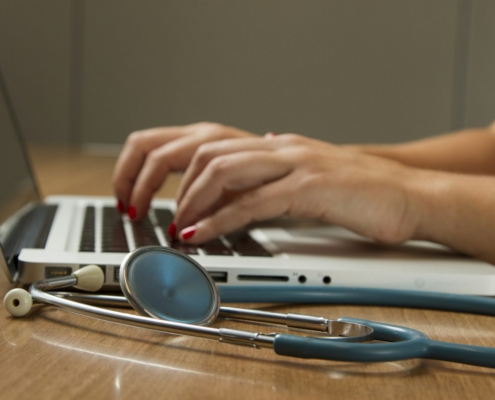 Compliance officer reviewing 42 CFR Part 2 SUD record-handling procedures on a laptop next to clinical documentation at a behavioral health program