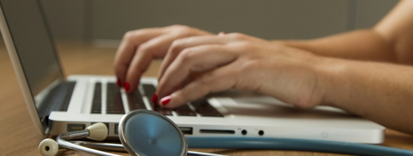 Compliance officer reviewing 42 CFR Part 2 SUD record-handling procedures on a laptop next to clinical documentation at a behavioral health program