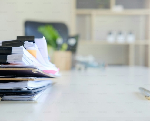 Stack of patient chart files and pen on a behavioral health compliance officer desk during an ASAM dimension documentation review