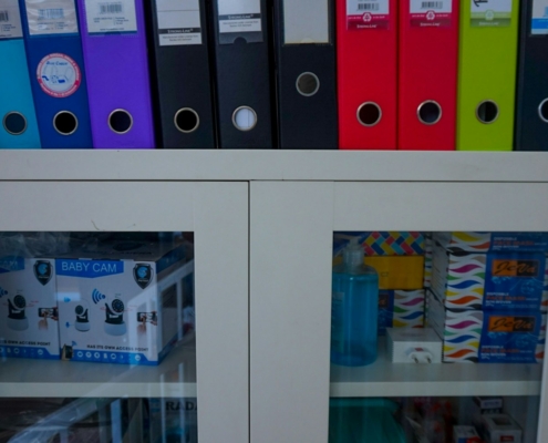 a glass door cabinet with a bunch of folders on top of it