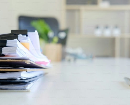 Stack of paper files and pen business equipment on office table.
