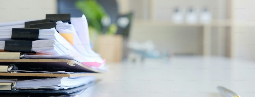Stack of paper files and pen business equipment on office table.
