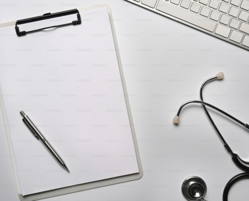 Empty clipboard and stethoscope on white table.