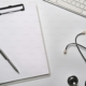 Empty clipboard and stethoscope on white table.