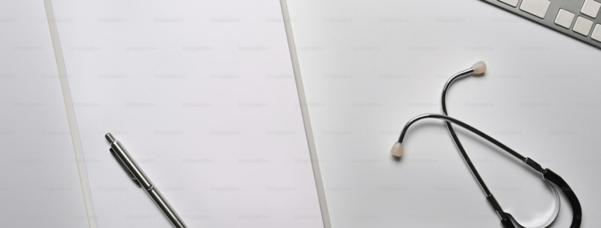 Empty clipboard and stethoscope on white table.