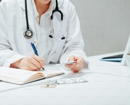 a woman in a white lab coat writing on a notebook