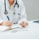 a woman in a white lab coat writing on a notebook