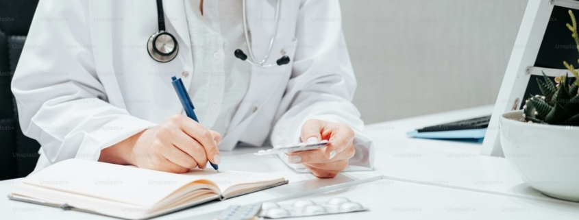 a woman in a white lab coat writing on a notebook