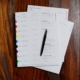 Tabbed credentialing documents and pen organized for provider profile data review