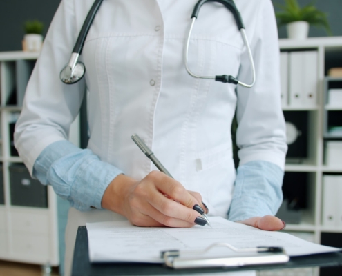 Clinician documenting utilization review notes on a patient chart in a medical office