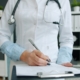 Clinician documenting utilization review notes on a patient chart in a medical office