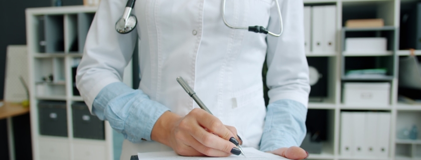 Clinician documenting utilization review notes on a patient chart in a medical office