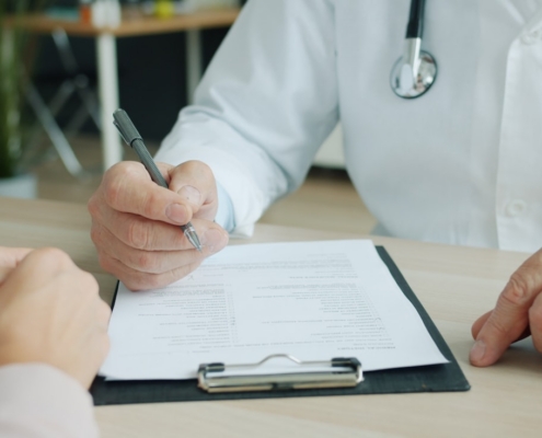 Clinician writing clinical notes on a patient chart during a documentation review
