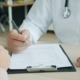 Clinician writing clinical notes on a patient chart during a documentation review
