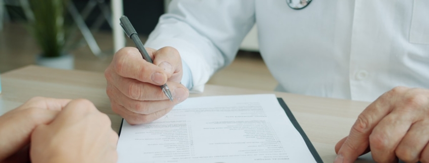 Clinician writing clinical notes on a patient chart during a documentation review
