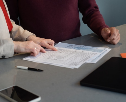 Two people at a table reviewing a licensing application form line by line for a rehab center