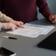 Two people at a table reviewing a licensing application form line by line for a rehab center