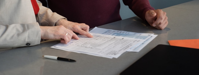 Two people at a table reviewing a licensing application form line by line for a rehab center