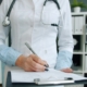 Clinician completing continued stay review documentation on a clipboard in an office lined with patient record binders
