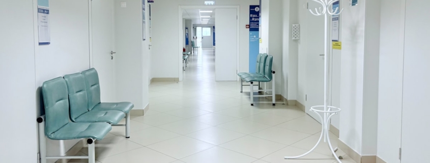 Bright corridor of a residential treatment facility with seating outside patient rooms, illustrating continued stay review documentation